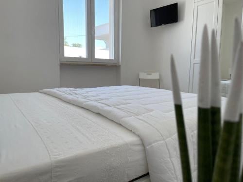 a white bed in a white room with a window at Villa Incanto Pina - Torre Canne in Torre Canne