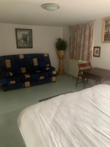 a bedroom with a bed and a table and a couch at Petite maison d Alsace in Brumath