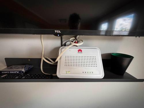 a desk with a computer monitor and a keyboard and a modem at Áshamrar in Hella