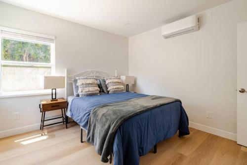 a bedroom with a bed with blue sheets and a window at 1 Palo Alto - Fully Furnished, AC, Private, Parking & Laundry in East Palo Alto