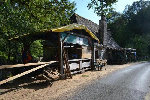 un bâtiment avec une tente sur le côté d'une route dans l'établissement air naturel de camping moulin de malesse caravane, à Saint-Privat