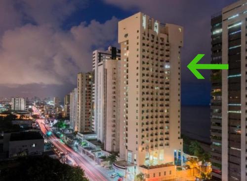a tall white building with a green arrow on it at Flat 10 andar Hotel Caesar Towers acesso direto praia in Recife