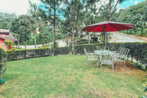 a table and chairs with an umbrella in a yard at Insta-Worthy Swiss House Staycation Crosswinds Tagaytay in Tagaytay