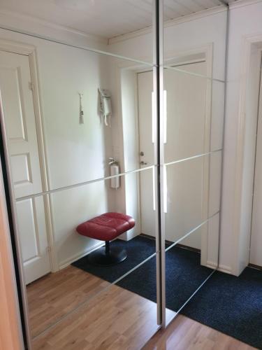 a shower room with a red stool and a glass wall at Lägenhet Bolum 7 in Broddetorp