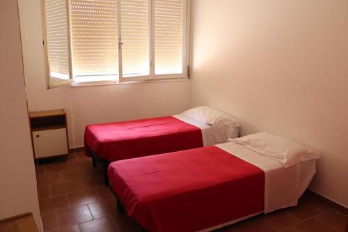 two beds in a room with a window at Ostello Paradiso EuroCamp in Cesenatico
