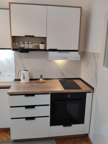 a kitchen with white cabinets and a stove top oven at DiV Apartman Jagodina in Jagodina