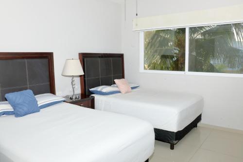 deux lits dans une chambre avec une fenêtre dans l'établissement Luxury Coral Dream, à Playa del Carmen