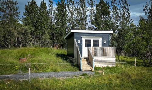 a small shed with a porch in a field at Áshamrar in Hella