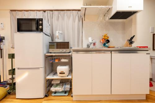 a kitchen with white cabinets and a refrigerator at Asakusa Stay in Tokyo