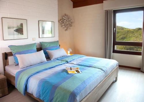 a bedroom with a bed with a book on it at Ferienhaus Dübbel Norderney in Norderney