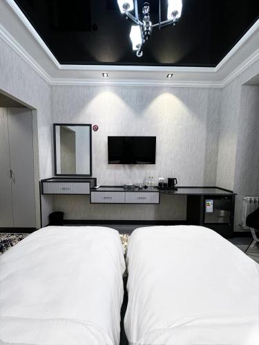 a bedroom with a bed and a tv on the wall at De Villa Hotel in Samarkand