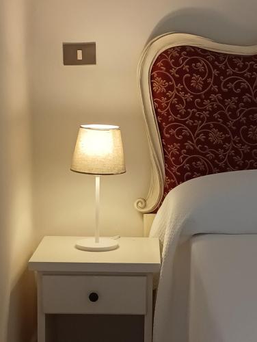 a lamp on a nightstand next to a bed at Hotel Corallo in Castiglioncello