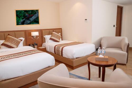 a hotel room with two beds and a chair at Nagarjun Resort - Embrace Tranquility Natures Retreat Beyond the City in Kathmandu
