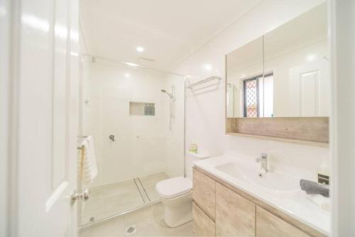 a white bathroom with a toilet and a sink at Springfield Breeze - Newly furnished home, Sunny Patio and BBQ in Goodna