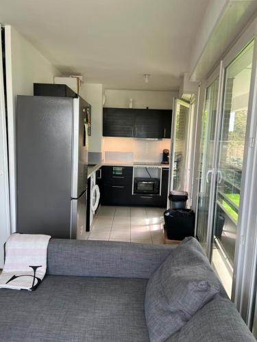 Il comprend une petite cuisine avec un canapé et un réfrigérateur. dans l'établissement AGON Lodge, à Rosny-sous-Bois