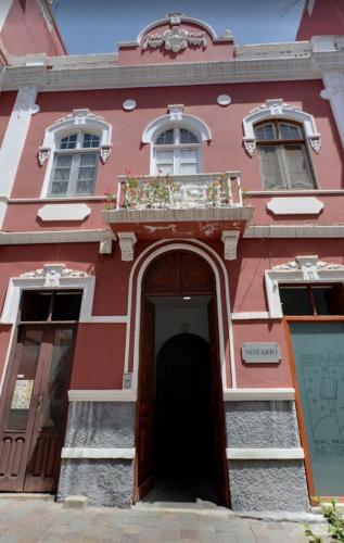 a red building with a door and a balcony at La Colonial in Vega de San Mateo