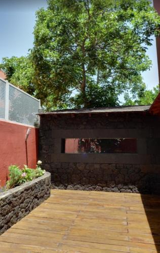 a brick wall with a wooden walkway next to a tree at La Colonial in Vega de San Mateo