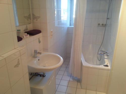ein weißes Badezimmer mit einem Waschbecken und einer Badewanne in der Unterkunft Hotel zur Sportsbar in Horn-Bad Meinberg