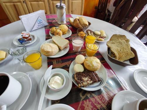 a table with plates of breakfast foods on it at Hosteria Los Cuartos in Tafí del Valle