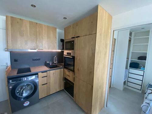 une cuisine avec des armoires en bois et une laveuse et une sécheuse dans l'établissement T2 entièrement rénové à 550m de la plage de La Faviere à Bormes-les-Mimosas, à Bormes-les-Mimosas
