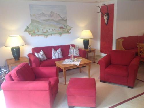 a living room with two red chairs and a table at Alpengruß in Wallgau