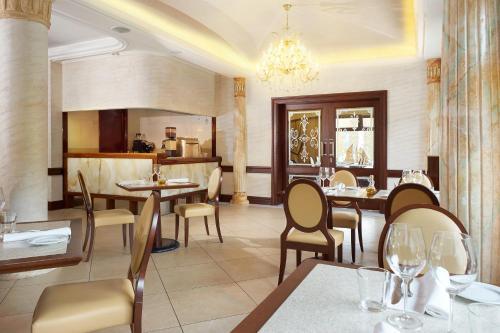 a restaurant with tables and chairs and a chandelier at Retro Riverside Wellness Resort in Karlovy Vary