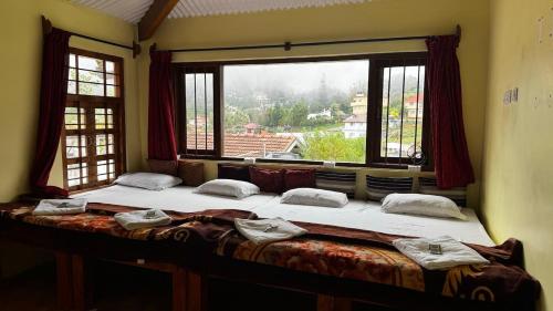 a large bed in a room with a large window at Trial Based Hotel in Coonoor