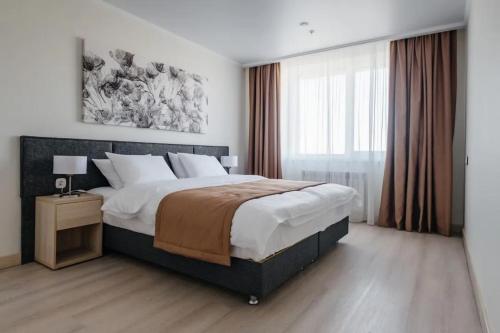 Un dormitorio con una cama grande y una ventana grande. en Yes Botanical Apartments, en Astana
