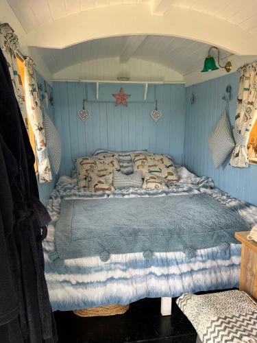 a bedroom with a bed in a blue room at The Hen House Shepherds hut with hot tub in Chittoe