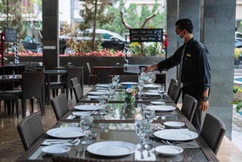a man on a phone at a table in a restaurant at Anugrah Hotel Sukabumi in Sukabumi