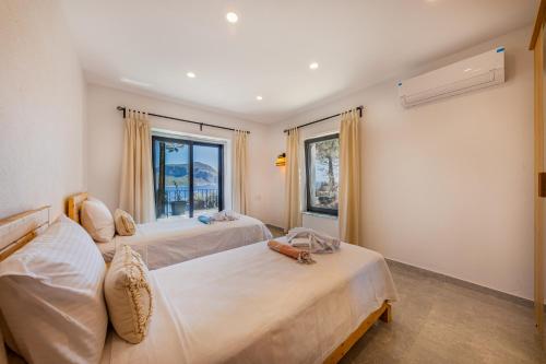 Dos camas en una habitación con dos ventanas. en Kalkan Villa Veranda, en Kalkan