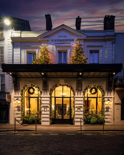 a white building with christmas trees in front of it at Hôtel & SPA Napoléon in Fontainebleau