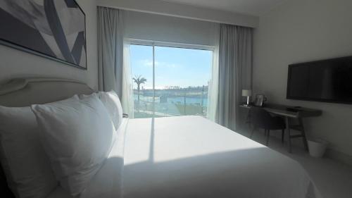 a hotel room with a bed and a large window at Marassi, Luxury Suite in Address Beach resort! service apartment in El Alamein