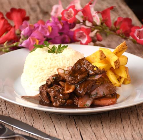 a plate of food with rice and meat and french fries at Lizzy Wasi Urubamba in Urubamba