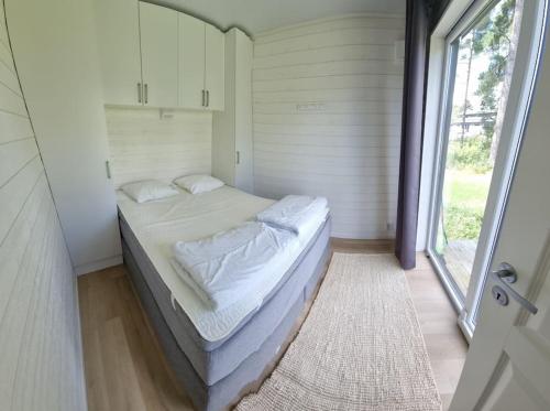 a small bed in a room with a window at Fridfullt läge, stuga med sjöutsikt in Säffle