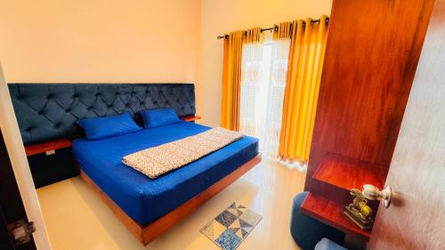 a bedroom with a blue bed and a window at MACA Canterbury Apartment in Gonapola