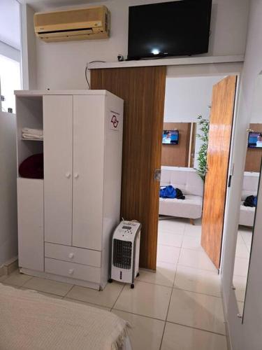 a living room with a white refrigerator and a tv at kitnet 103 com ar e 2 tv smart in Montes Claros