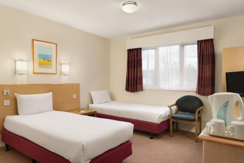 a hotel room with two beds and a tv at Days Inn Hotel Warwick South - Southbound M40 in Warwick