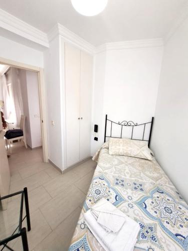 a white bedroom with a bed and a chair at Apartamento Lola2 in Nerja