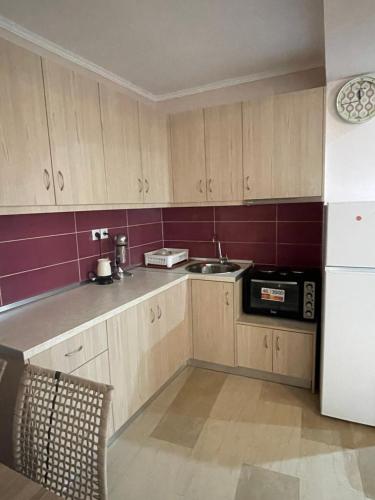 a kitchen with wooden cabinets and a sink and a refrigerator at Anastelia Apartments - 1 in Olympiada