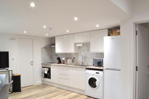 a kitchen with white cabinets and a washer and dryer at New Flat near Luton Airport FREE PARKING in Luton