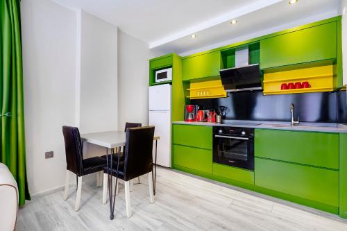 a kitchen with green cabinets and a table and chairs at Twin Apart Hotel in Alanya
