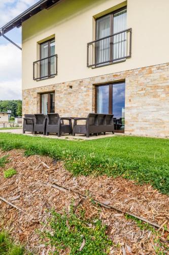 a patio with black chairs in front of a house at Apartmán Simon - Horský Resort Buková Hora - Červená Voda in Červená Voda