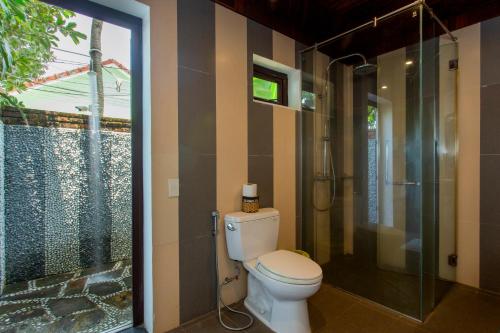 a bathroom with a toilet and a glass shower at Hoi An Garden Villas in Hoi An