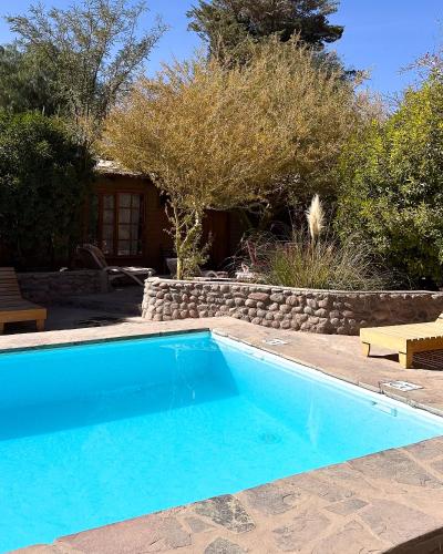 a blue swimming pool in front of a house at Hotel Corvatsch Chile in San Pedro de Atacama