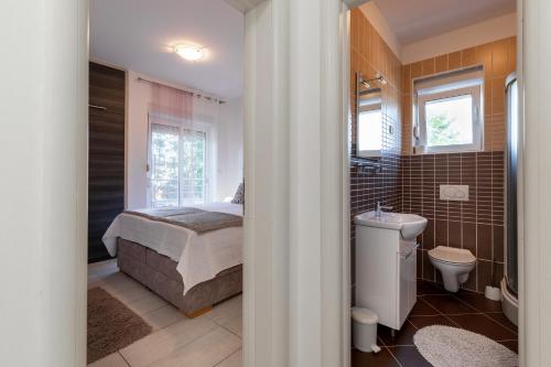 a bedroom with a bed and a toilet and a sink at M&B Green Oasis with pool and jacuzzi in Bibinje