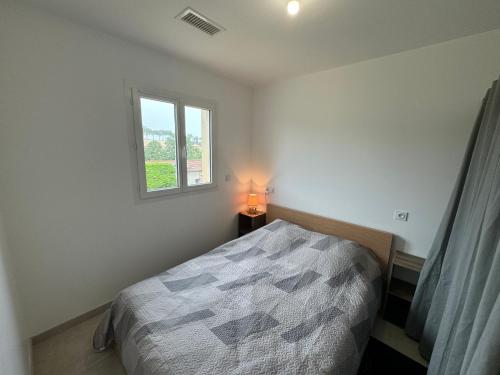 une chambre avec un lit avec une lampe et une fenêtre dans l'établissement La Gourgotte, à Ajac