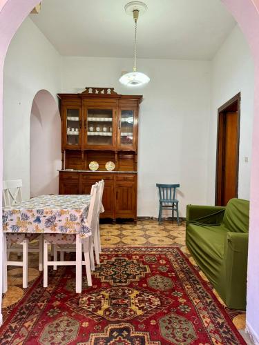 a dining room with a table and a green couch at House Le Gallinelle in Assemini