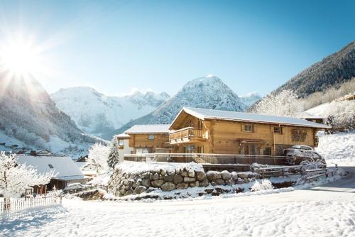 a wooden house in the snow with mountains in the background at URALP Royal in Brand