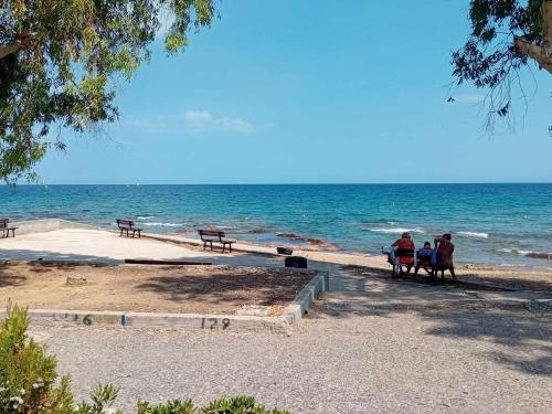 a group of people sitting on benches on the beach at Catherine's house in Artemida